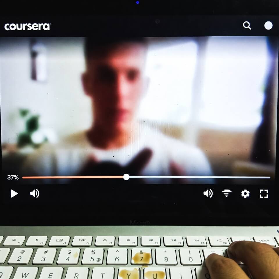 Paused Coursera video at 37% with coffee-stained keyboard